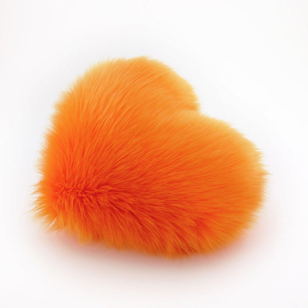 Side view of an Orange faux fur heart shaped decorative throw pillow.