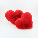 A pair of a Red fluffy plush heart shaped decorative pillows.