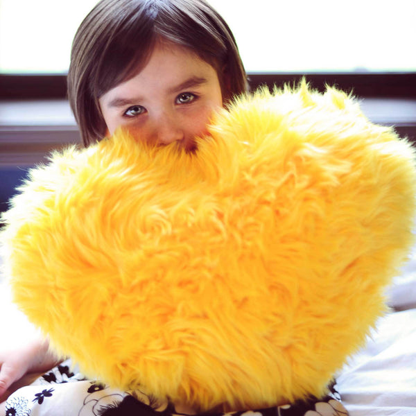 Girl with Yellow faux fur heart shaped pillow.