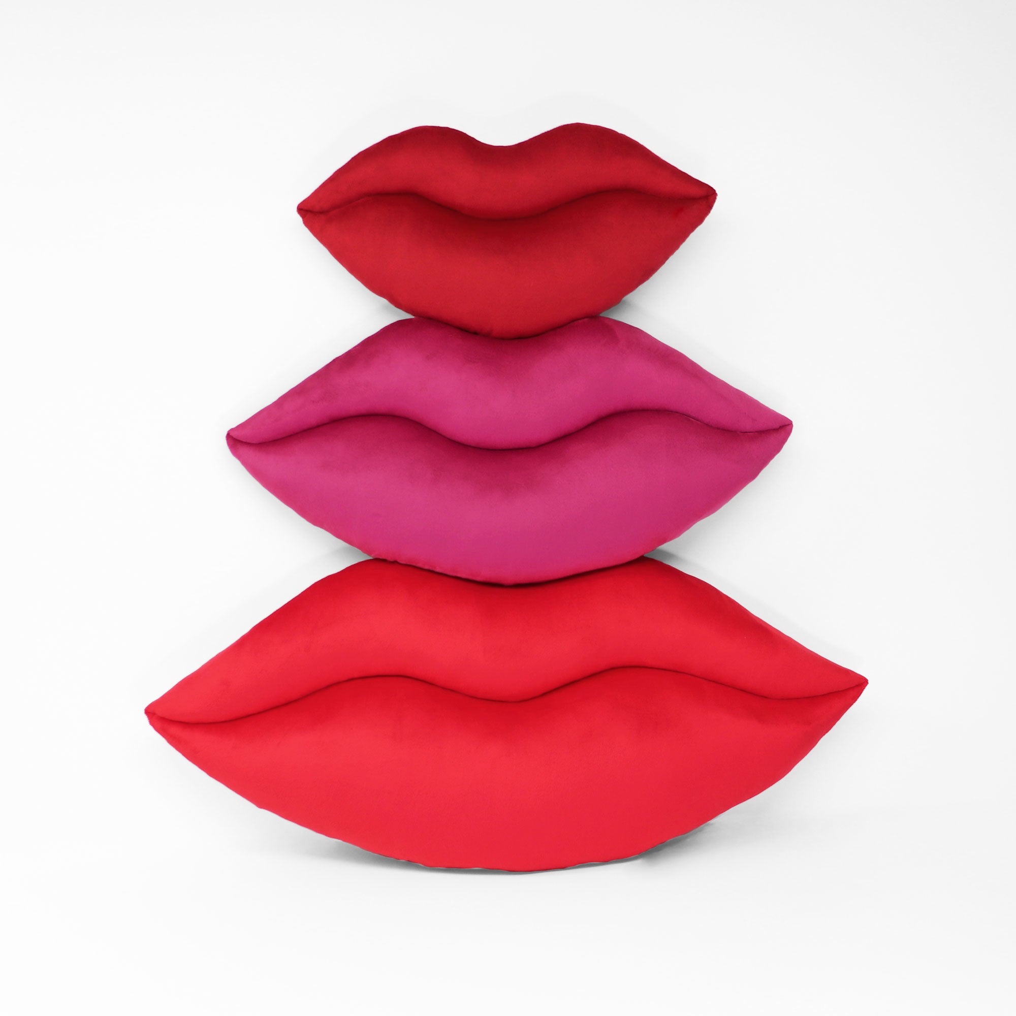 Lips shaped decorative throw pillows shown in three colors and three sizes.